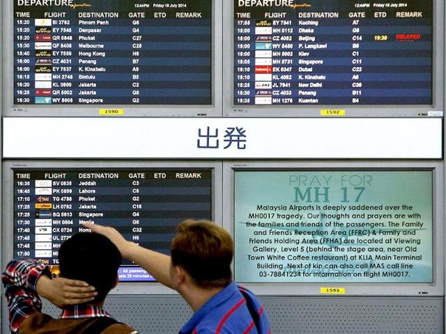 Bystanders look at a board displaying flight information and a "Pray for MH17" message. (Reuters Photo)