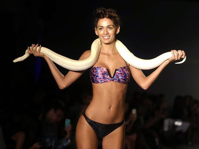 A model walks down the runway with a live snake wearing swimwear designed by We Are Handsome. (AP Photo) 