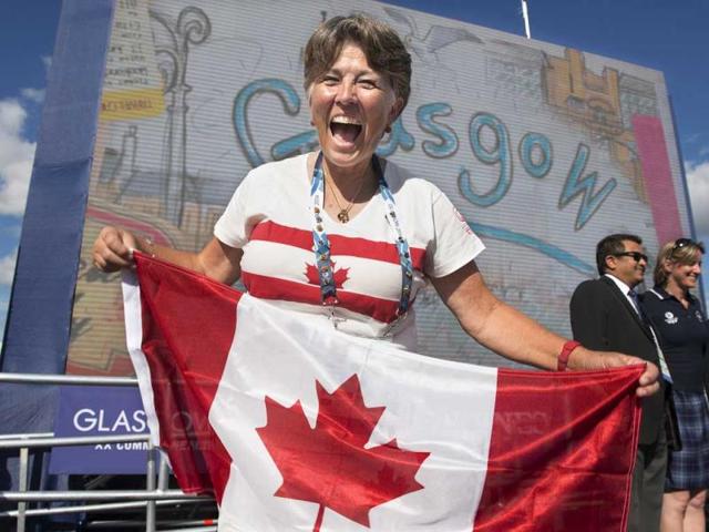 Trap shooter Susan Nattrass smiles as she display the Canadian flag as members of the Canadian team attend their welcome ceremony at the Commonwealth Games in Glasgow. AP Photo