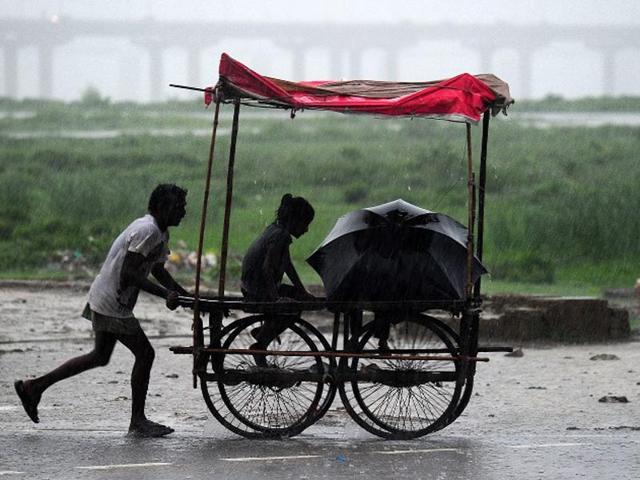 India, Allahabad: An Indian man pushes his trolley during heavy rain in Allahabad on July 19, 2014. (AFP/Sanjay Kanojia)