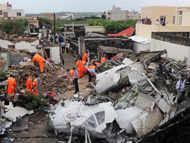 Taiwan, Magong: Rescue workers and firefighters search through the wreckage where TransAsia Airways flight GE222 crashed the night before near the airport at Magong on the Penghu island chain on July 24, 2014. (AFP/Sam Yeh)