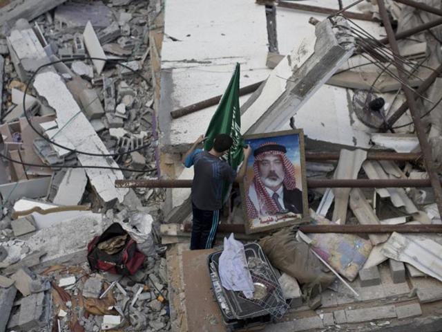 A Palestinian man displays an Islamist Hamas movement flag and a portrait of Hamas top leader in Gaza, Ismail Haniya, on the rubble of the latter's house after it was hit by an overnight Israeli air strike on July 29, 2014 in Gaza City. (AFP/Mahmud Hams)
