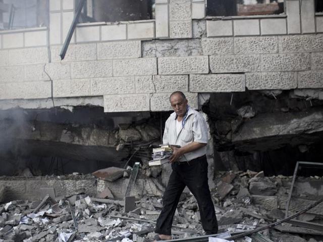 A Palestinian man holds copies of the Koran, Islam's holy book, as he inspects the rubble of a destroyed mosque hit by an Israeli air strike on July 29, 2014, in Gaza City. (AFP/Mahmud Hams)