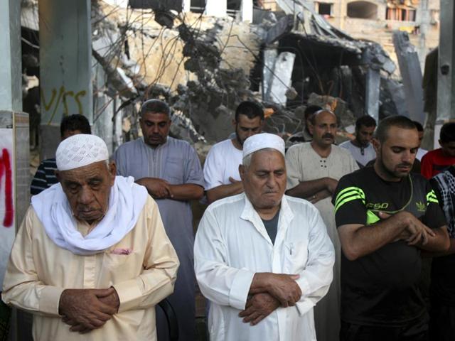 Palestinians participate in early morning prayer during the first day of Eid al-Fitr inside the destroyed Al Farouk mosque which was destroyed by an overnight Israeli strike in Rafah on July 29, 2014. (AP Photo/Eyad Baba)