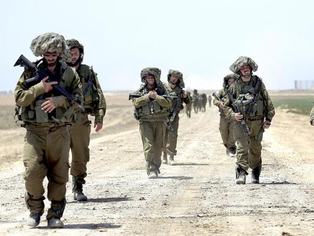 Israeli-soldiers-walk-next-to-tanks-stationed-on-a-field-outside-the-central-Gaza-Strip-Reuters-photo