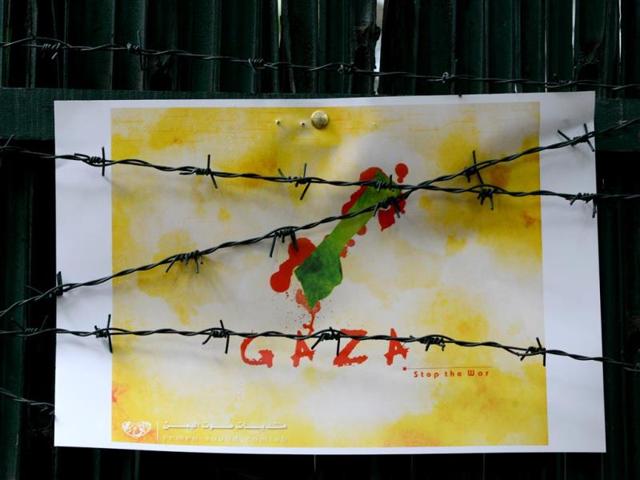 Barbed wire is stretched across a 'stop the war in Gaza' poster displayed during a cultural event held by members of the Safdar Hashmi Memorial Trust in protest against the Israeli operation in Gaza, in New Delhi. (AFP Photo)