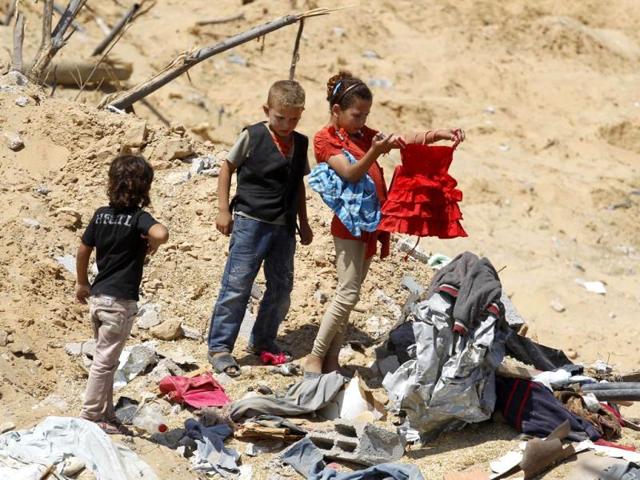 A Palestinian girl salvages clothes from the rubble of their destroyed home following an Israeli air strike on Abasan, east of the southern Gaza Strip town of Khan Yunis. (AFP photo/Said Khatib)