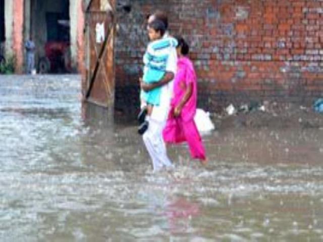 People make their way through a during rainfall in Amritsar on Saturday. Sameer Sehgal/HT