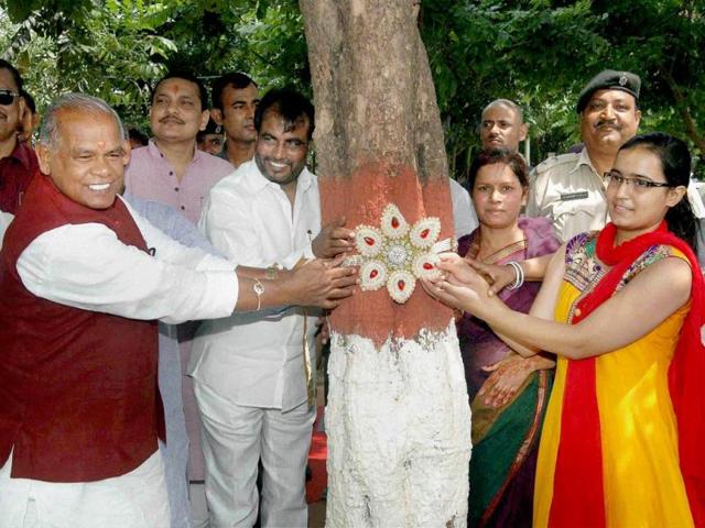 Bihar chief minister Jitan Ram Manjhi tries rakhi on a tree at an eco park on the occasion of Raksha Bandhan in Patna. (PTI Photo)