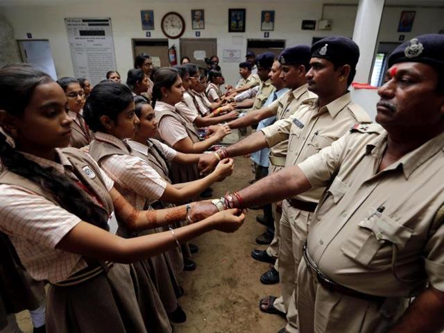 Schoolgirls tie rakhis onto the wrists of Indian police personnel inside a police station on Raksha Bandhan in Ahmedabad. (Reuters Photo)