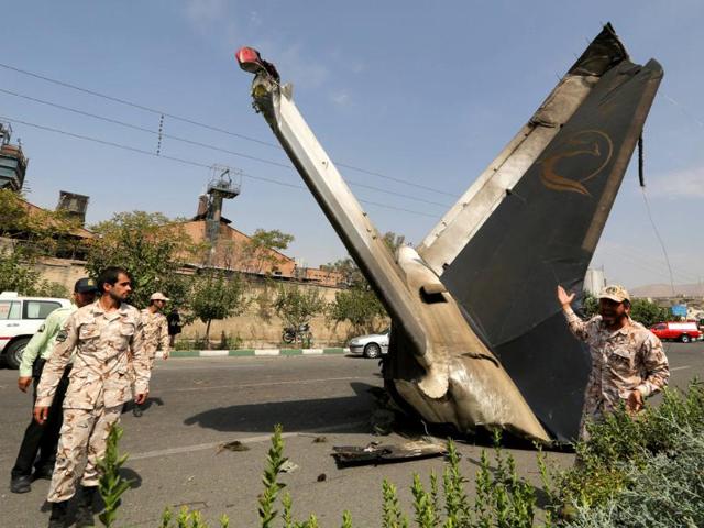 A member of the Iranian Revolutionary Guards reacts as he stands next to the remains of a plane that crashed near Tehran's Mehrabad airport. (AFP photo)