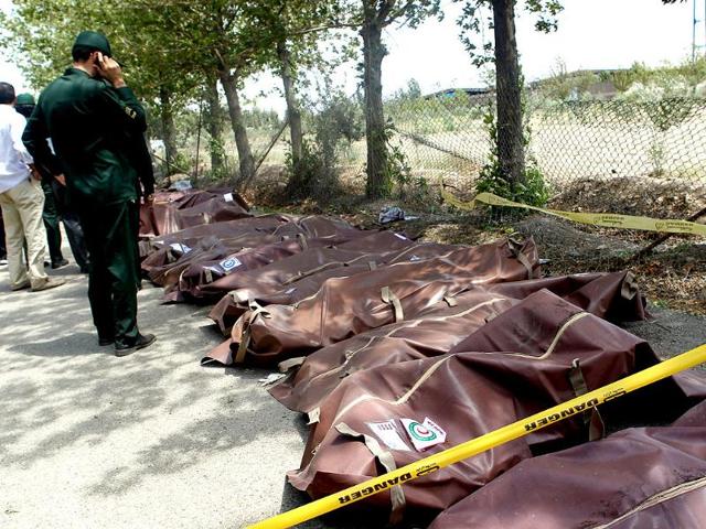 A member of Iranian Revolutionary Guards talks on his mobile phone as he looks at the bodies of victims of a passenger plane crash near the capital Tehran, Iran. (AP photo)