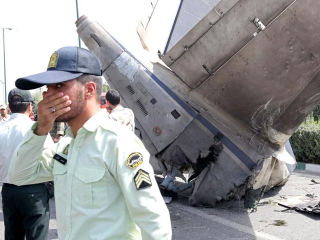Iranian security forces stand next to the remains of a plane as they secure the scene of a crash near Tehran's Mehrabad airport. (AFP photo)