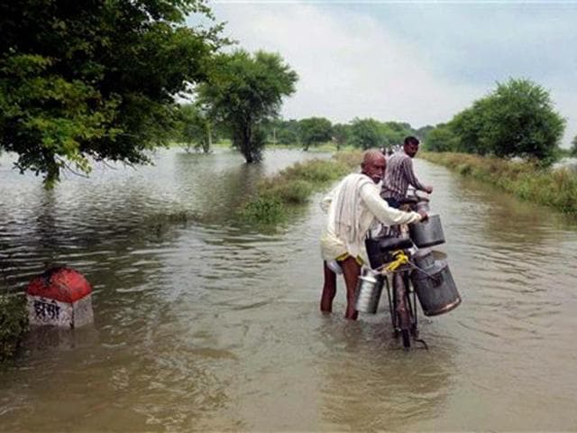 People wading through a waterlogged road after water level of river Ganga rose significantly, at Jhunsi village near Allahabad. (PTI Photo)