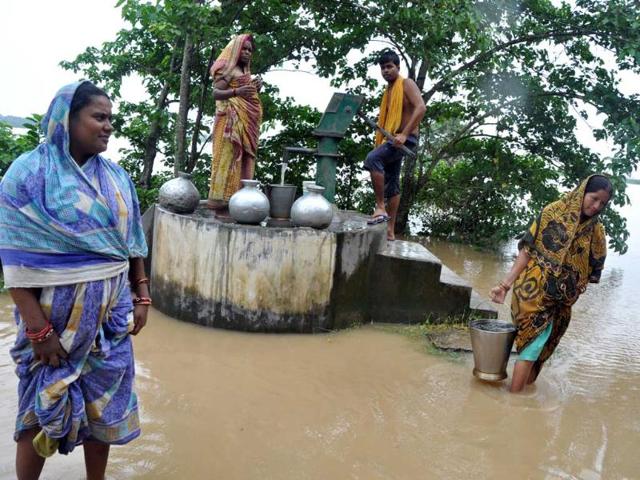 A woman wades through flood water as she carries drinking water collected from a handpump in Batira village, Kendrapada district. (Arabinda Mahapatra/HT Photo)