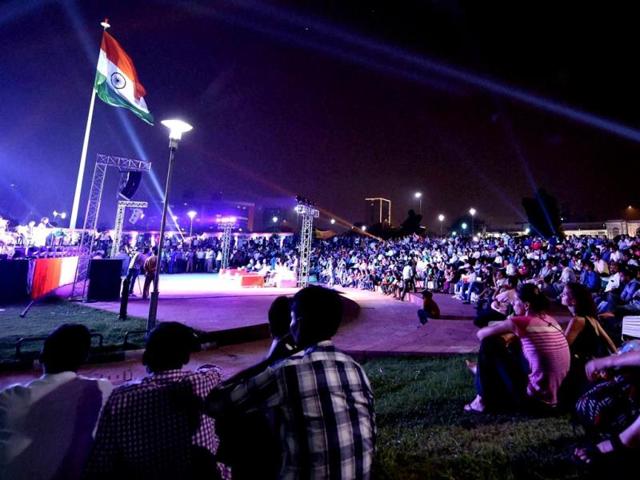 People enjoy music as the national flag flatters during the inauguration of the week-long celebrations of Independence Day at the Central Park in New Delhi. PTI Photo