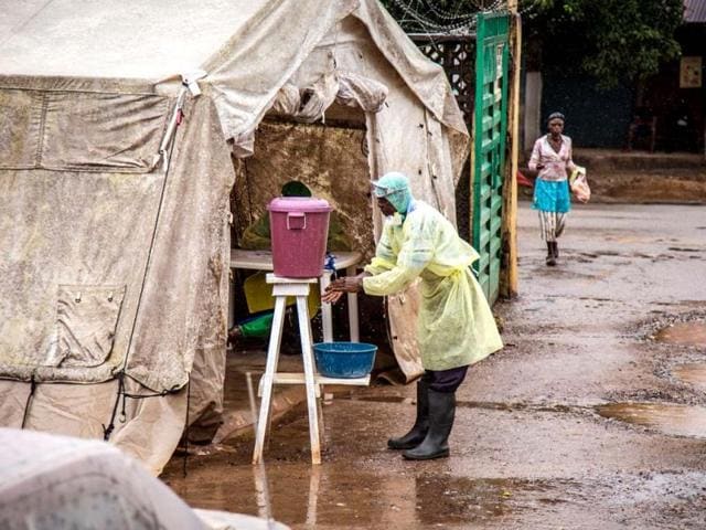 In this photo taken Monday, Aug. 11, 2014, a health worker cleans his hands with chlorinated water before entering a Ebola screening tent, at the Kenema Government Hospital situated in the Eastern Province around 300 kilometer (186 miles) from the capital city of Freetown in Kenema, Sierra Leone. (AP Photo)