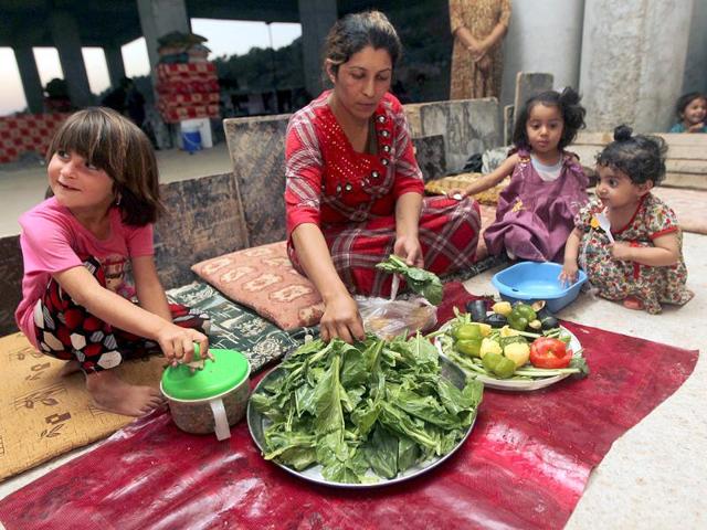 An Iraqi woman from the Yazidi community prepares dinner for her children in a building under construction used as shelter after their fled their hometown of Sinjar which was attacked by Sunni militants from the Islamic state (IS). (AFP photo)