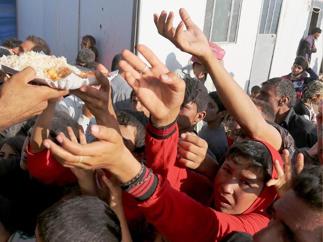 Displaced Iraqis from the Yazidi community gather for food at the Nowruz camp, in Derike, Syria. (AP photo)