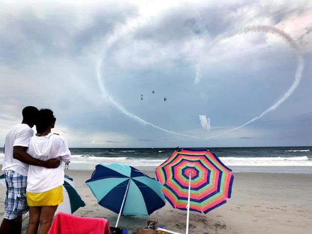 Phil Terry and Linda Laosongkram, both of Galloway Township, New Jersy, watch the Geico Skytypers perform a practice run in preparation for the Thunder Over the Boardwalk air show from the beach. (AP photo)