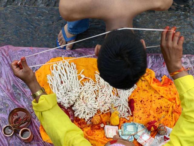A Nepalese devotee receives a Janai or sacred thread, which is a yellow cotton string worn across the chest or tied around the wrist of the right hand, from a priest during the Janai Purnima Festival at The Pashupatinath Temple in Kathmandu. (AFP photo)