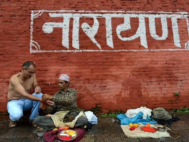 A Nepalese devotee receives a Janai or sacred thread, which is a yellow cotton string worn across the chest or tied around the wrist of the right hand, from a priest during the Janai Purnima Festival at The Pashupatinath Temple in Kathmandu. (AFP photo)