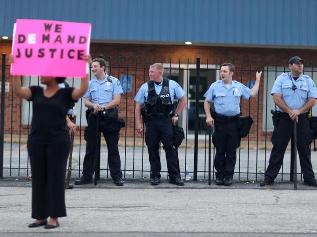 A demonstrator holds a sign reading, "We Demand Justice", in front of a line of police as demonstrators continue to make their voices heard in the shooting death of Michael Brown. (AFP Photo)