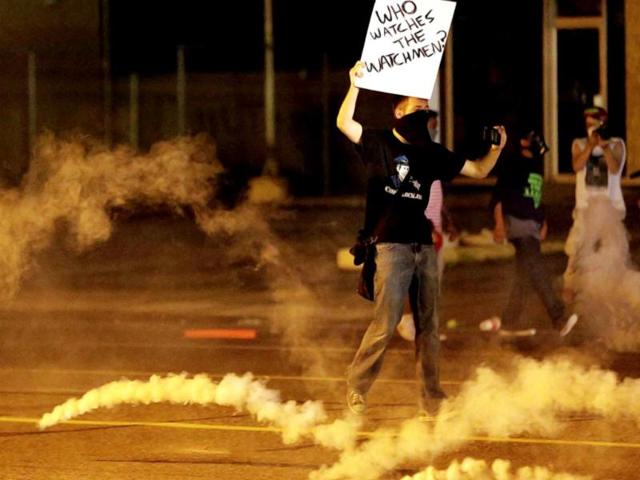 A protester stands in the street after police fired tear gas to disperse a crowd during a protest for Michael Brown, who was killed by a police officer last Saturday in Ferguson, Mo. (AP Photo)