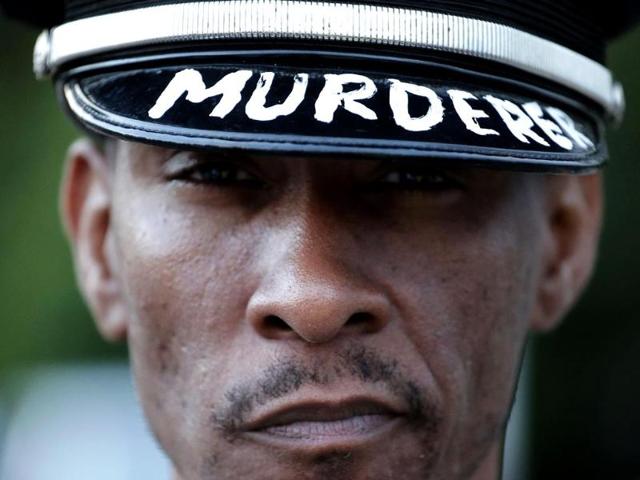 A man wearing a police hat protests Sunday for Michael Brown, who was killed by a police officer last Saturday in Ferguson, Mo. (AP Photo)
