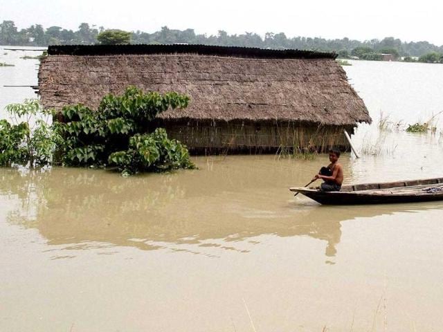Two boys paddle their boat through flood affected Pabhokati village after a heavy downpour in Morigaon distrct, Assam. (PTI Photo)