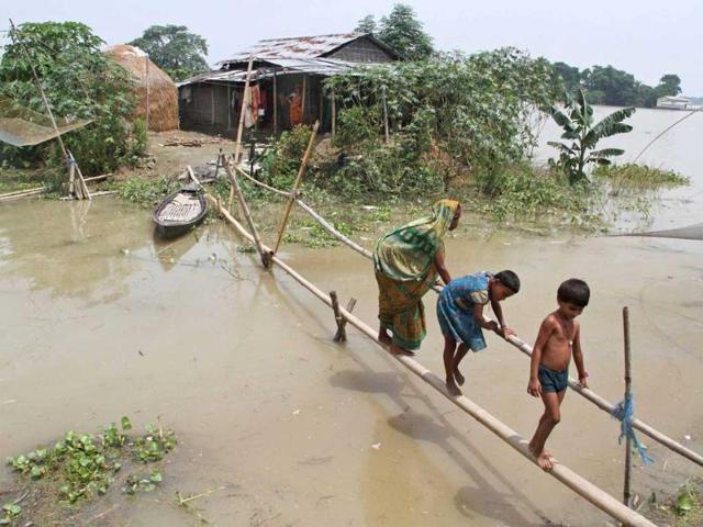 Villagers use a makeshift bamboo bridge to move across flooded areas of Morigaon district in Assam. (Reuters Photo)