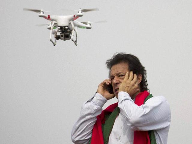 Pakistan's cricketer-turned-politician Imran Khan talks over a phone as a camera-equipped drone hovers outside a parliament in Islamabad. (AP Photo)