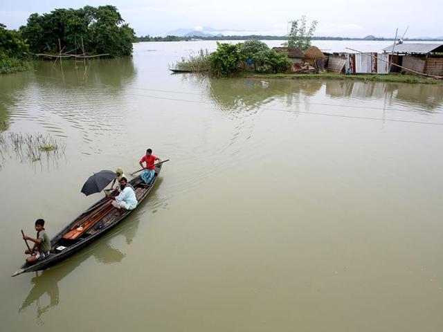 A villagers row a country boat past houses cut off by flood waters at Ashigarh village in Morigaon district of north eastern Assam state, India. (AP Photo)