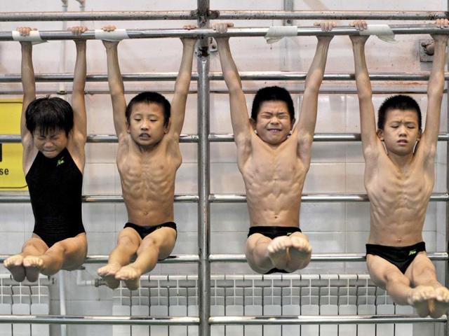 Young divers stretch as they hang from a steel bar during a training session at a sports school in Hefei, Anhui province. (Reuters Photo)