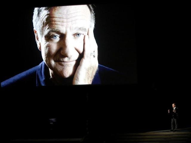 Billy Crystal takes the stage to pay tribute to the late Robin Williams, shown on a large screen, during the Emmy Awrads. (Reuters)
