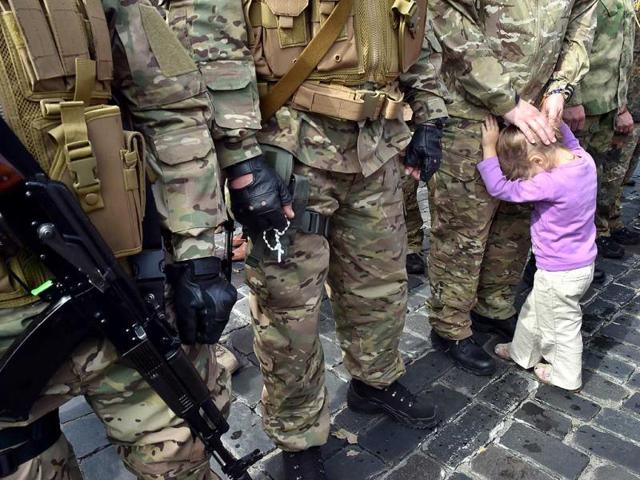 The child of a Sich special volunteer battalion member holds her father during an oath-taking and farewell ceremony in Kiev. (AFP Photo)
