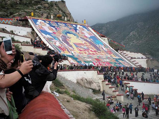 Tibetan Buddhists and tourists view a huge Thangka, a religious silk embroidery or painting displaying a Buddha portrait, during the Shoton Festival at Zhaibung Monastery in Lhasa.(REUTERS/China Daily)