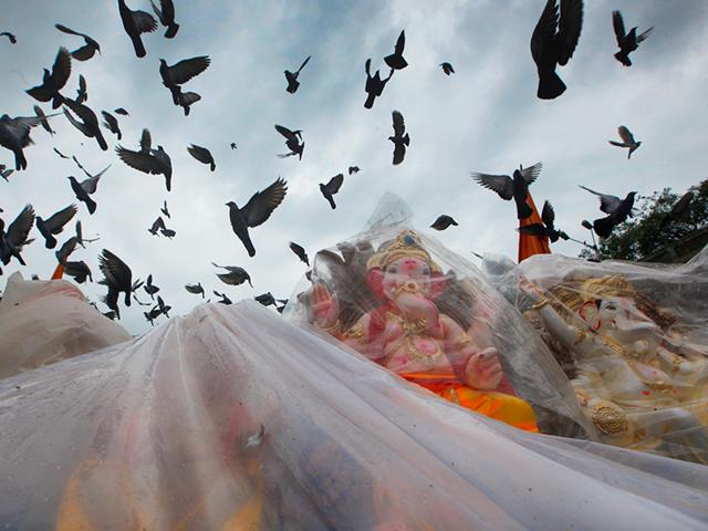 Idols of Lord Ganesh put on sale as pigeons fly at the back in Kabutarkhana, Dadar, Mumbai, India on Tuesday, August 26, 2014. (Hindustan Times/Kalpak Pathak)