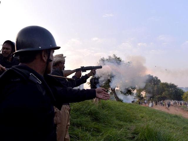 A Pakistani riot policeman fires a tear gas shell on the supporters near Nawaz Sharif's residence in Islamabad on Sunday. At least 300 people were wounded in clashes between the police and protesters, according to hospital officials, as a fortnight-long political impasse took a violent turn. (AFP PHOTO)