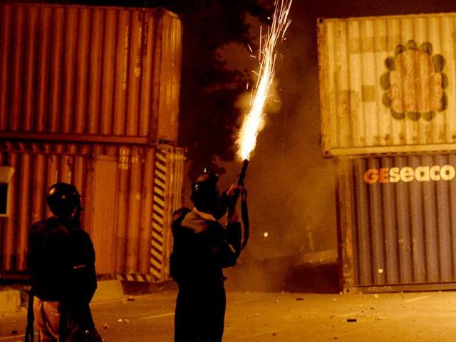 A Pakistani policeman fires a tear gas shell The violence, which began late Saturday and continued early Sunday, broke out after around 25,000 people marched from parliament to Nawaz Sharif's house, where some attempted to remove barricades around it with cranes, an AFP reporter at the scene said. (AFP PHOTO)