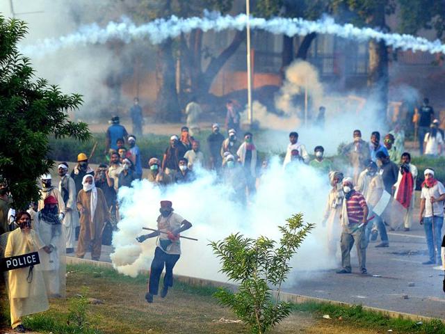A Pakistani supporter of Tahir ul Qadri (C) throws a tear gas shell towards the police during clashes with security forces near the PM's residence in Islamabad on Sunday. (AFP PHOTO)