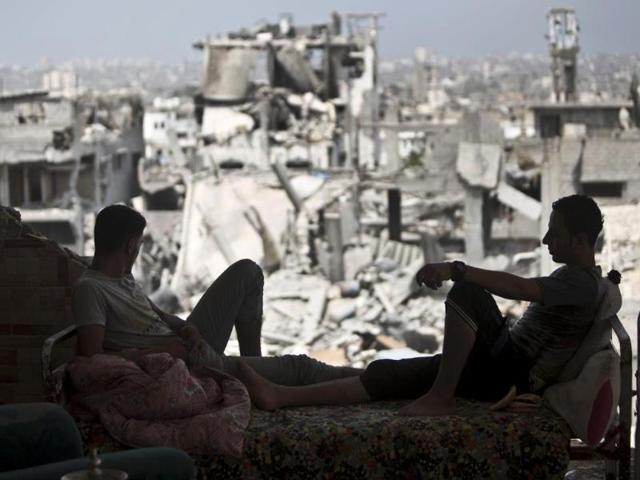 Palestinians sit inside their destroyed house after returning home in the Tufah neighbourhood in eastern Gaza City. (AFP Photo)