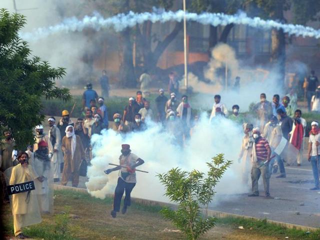 A Pakistani supporter of cleric Tahir ul Qadri (C) returns a tear gas shell towards police during clashes with security forces near the prime minister's residence in Islamabad. (AFP Photo)