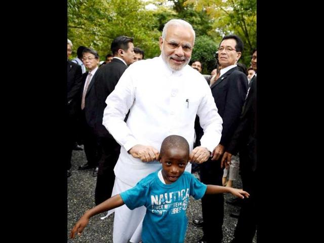 PM Modi shares a light moment with a child during his visit at Golden Pavilion, Buddhist temple in Kyoto. (PTI Photo)