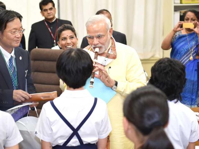 PM Modi plays a flute as he visits a music class in an elementary school in Tokyo. (AFP Photo)