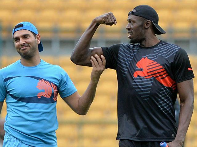 Jamaican Olympic Champion sprinter Usain Bolt flexes his biceps while Indian cricketer Yuvraj Singh looks on during a practice session prior to a four-over exhibition cricket match at Chinnaswamy Stadium between two teams led by the players in Bangalore on September 2, 2014. (AFP/Manjunath Kiran)