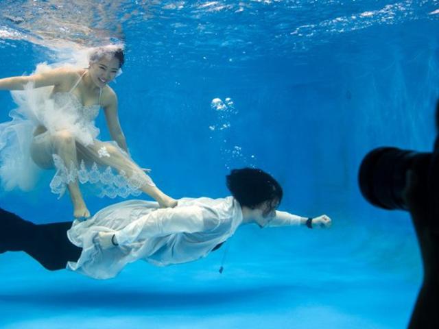 Qin Riyang (bottom) and Leng Yuting try to maintain balance to strike a pose during the wedding photo shoot in Shanghai. (AFP/Jonahhes Eisele)