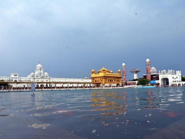 Indian Sikh devotees pay their respects during heavy rain at the Sikh Shrine Golden temple in Amritsar. (AFP/Narinder Nanu)