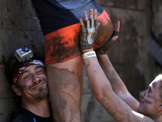 Participants climb over a wall at the "Tough Mudder" endurance event series in Arnsberg. (Reuters Photo)