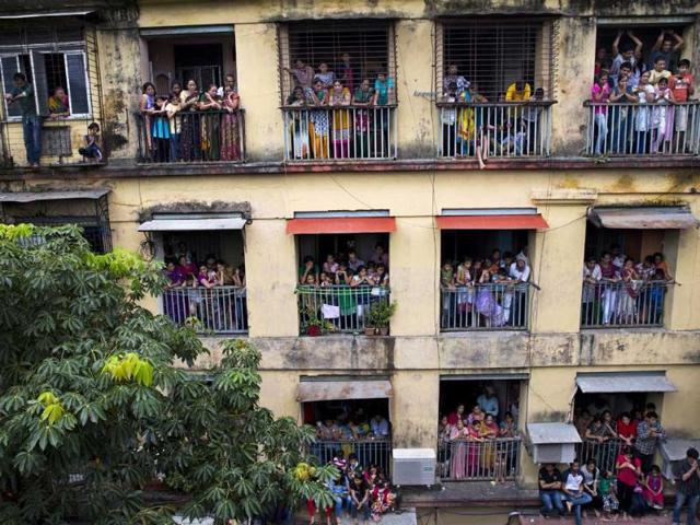 People look on from their houses as devotees carry Lord Ganesh idols for immersion in Mumbai on Monday. (AP Photo)